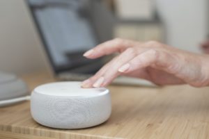 A woman’s hand turns down the volume on an Amazon Alexa device